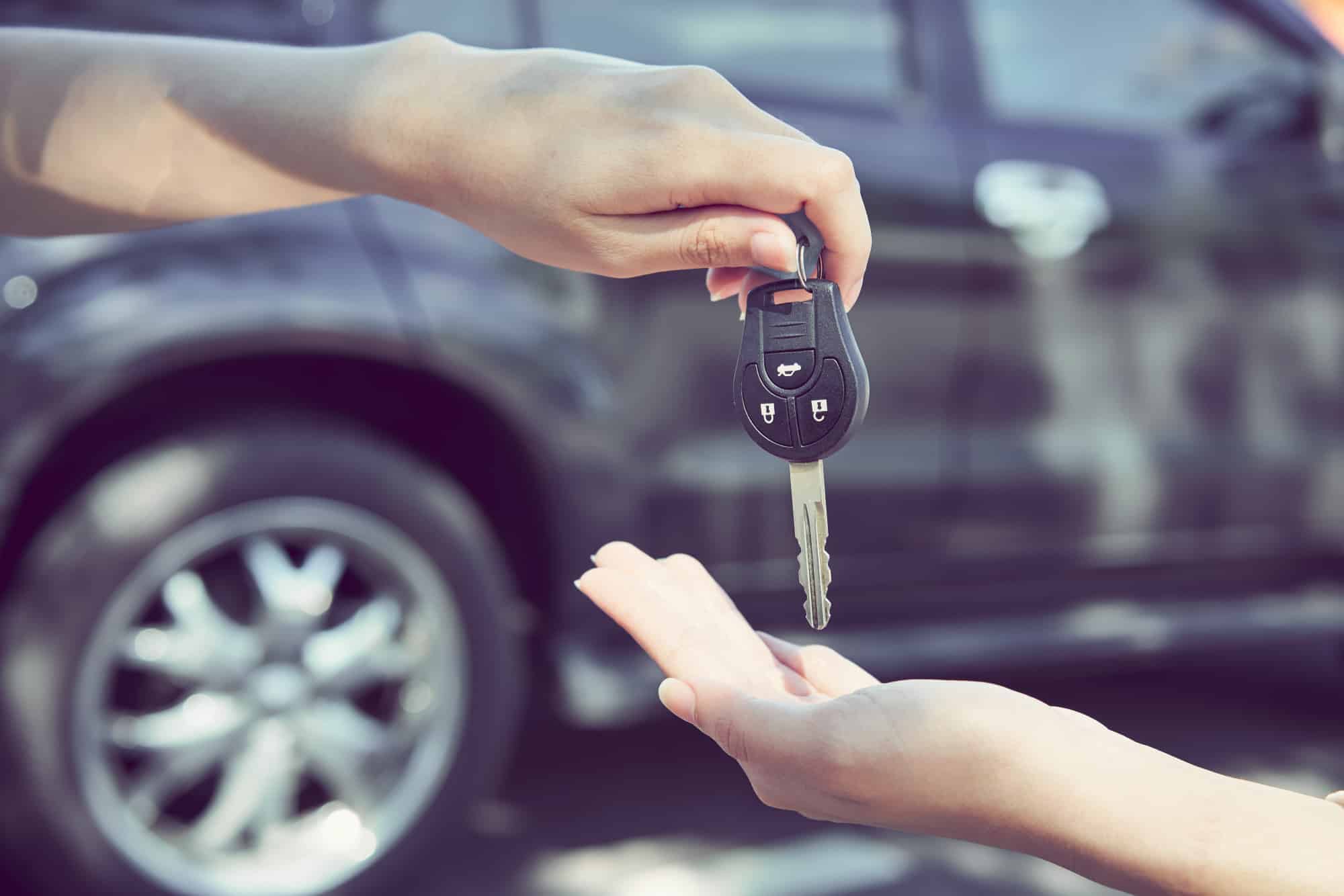 Technician Replacing Car Keys: Woman's hand give the car key and blurred background.